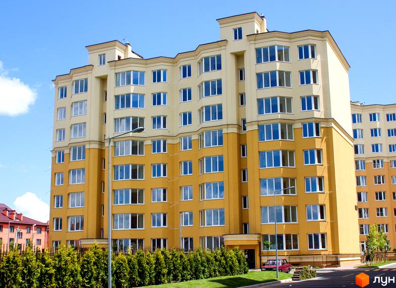 Житловий комплекс Софія Сіті. Багатоповерховий будинок жовто-бежевого кольору з великою кількістю вікон. Навколо будинку зелені насадження та доглянута територія.