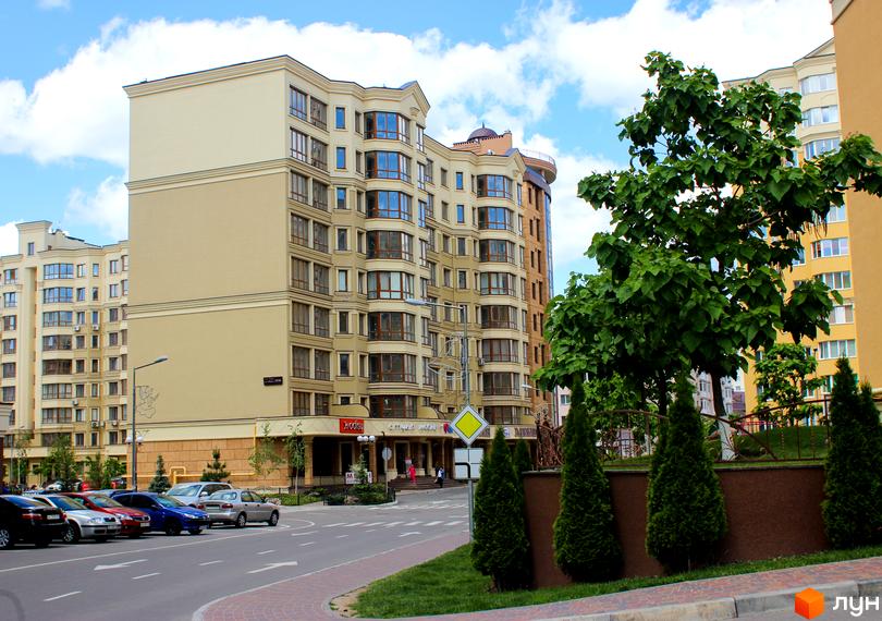 Житловий комплекс Софія Сіті з фасадами світло-бежевого кольору та панорамними вікнами. Прибудинкова територія з зеленими насадженнями та парковкою.