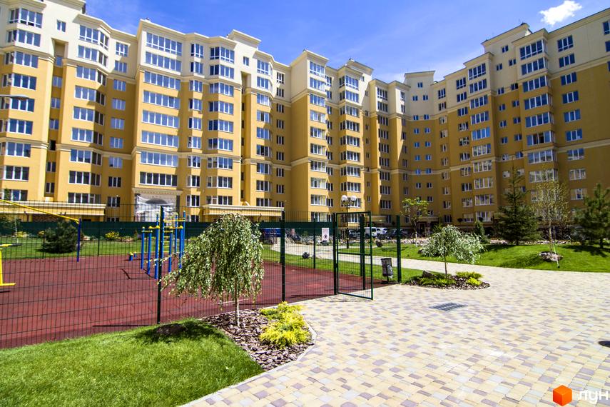 Житловий комплекс Софія Клубний із жовтим фасадом та білими елементами. На прибудинковій території розташований дитячий майданчик та зелені насадження.