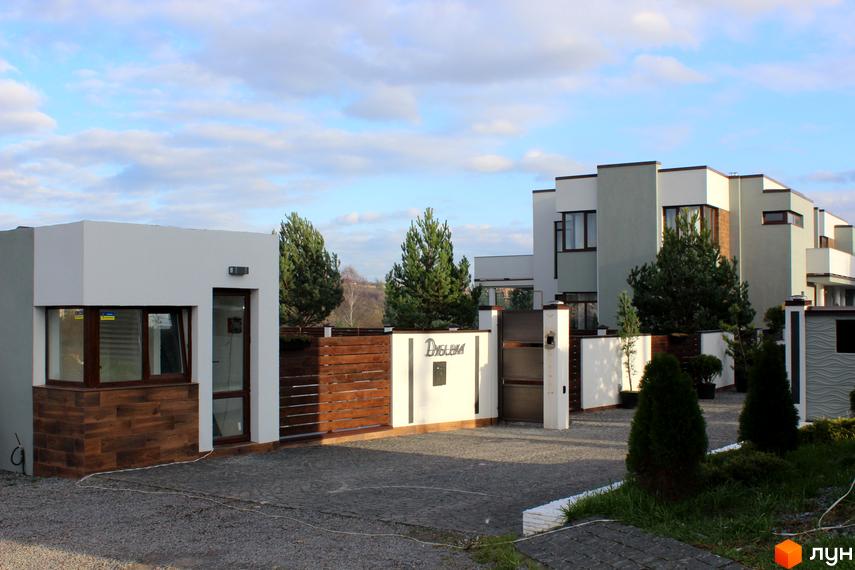 Котеджне містечко Riviera: фасади будинків з великими вікнами та дерев'яними елементами, огороджена територія з воротами та охоронним будинком.