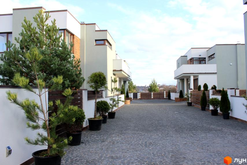 Котеджне містечко КМ Riviera: фасади будинків та доглянута прибудинкова територія з бруківкою та зеленими насадженнями. Огляд екстер'єру новобудови.