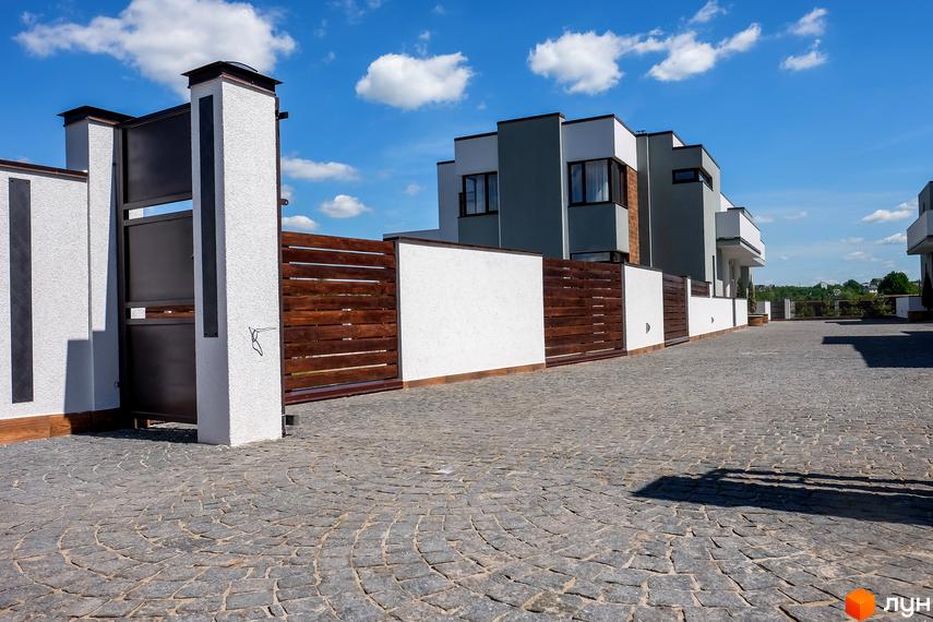 Котеджне містечко Riviera: фасад будівель з сірими та білими елементами, дерев'яний паркан та бруківка на території. Фото новобудови.