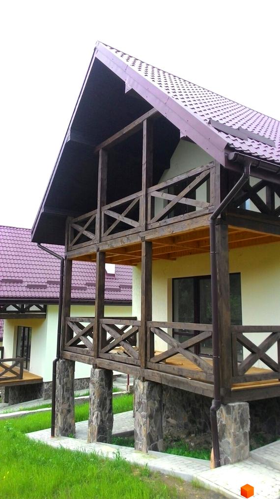 Будинок з дерев'яною верандою та кам'яним цоколем на вулиці Грушевського. Зелена прибудинкова територія з доріжками.