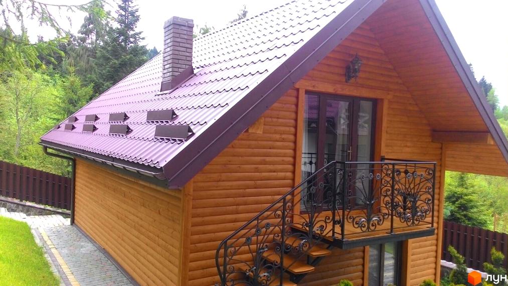 Будинок з дерев'яними стінами та фіолетовим дахом, прибудинкова територія з парканом та зеленими насадженнями.