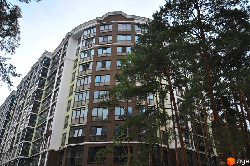 Зображення фасаду Житлового комплексу Лісова казка. Багатоповерховий будинок з великими вікнами, поруч дерева.