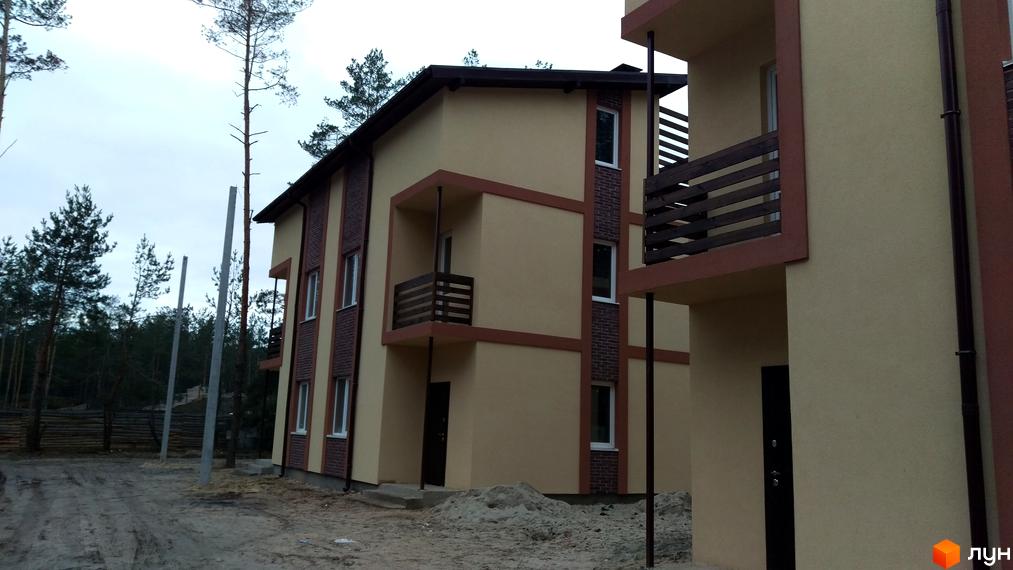 Зображення Котеджного містечка Лісове-2. Двоповерхові будинки з балконами та коричневими вставками на фасаді, поруч ліс.