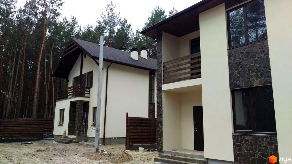 Котеджне містечко КМ Лісове-3. Зовнішній вигляд двоповерхових будинків з дерев'яними балконними огородженнями та кам'яним оздобленням фасадів на тлі лісу.