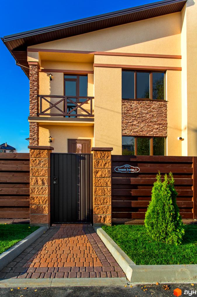 Котеджне містечко Злагода: фасади будинків та доглянута прибудинкова територія з зеленим газоном і бруківкою.