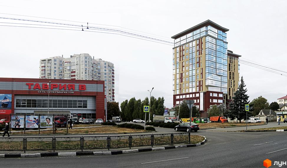 Новобудова ЖК Кристал з цегляним фасадом та скляними елементами. Навколо новобудови розташовані дерева та дорога з автомобілями.