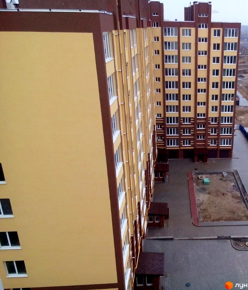 Житловий комплекс Авіла: багатоповерховий будинок з жовтим фасадом та коричневими елементами. Прибудинкова територія з асфальтованими доріжками.