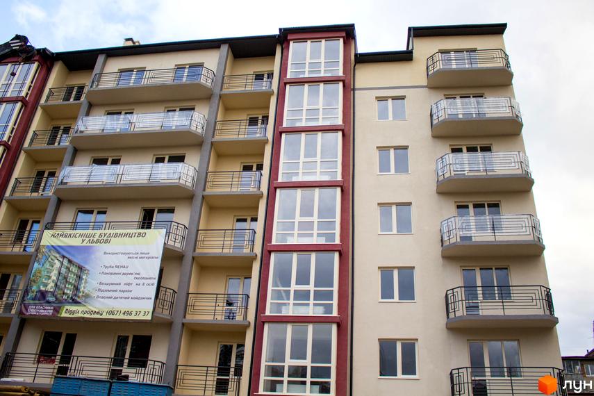 Фасад житлового комплексу на вул. Єрошенка, 14 у Львові з балконами та великими вікнами. Зовнішній вигляд будівлі з елементами червоного кольору.