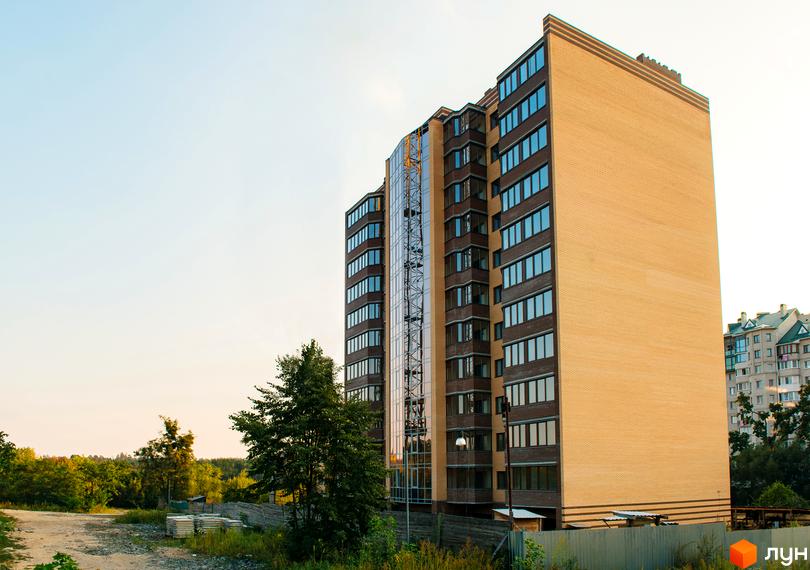 Новобудова ЖК Тетерівський Бульвар з цегляним фасадом та скляною секцією. Навколо зелені насадження та облаштована територія.