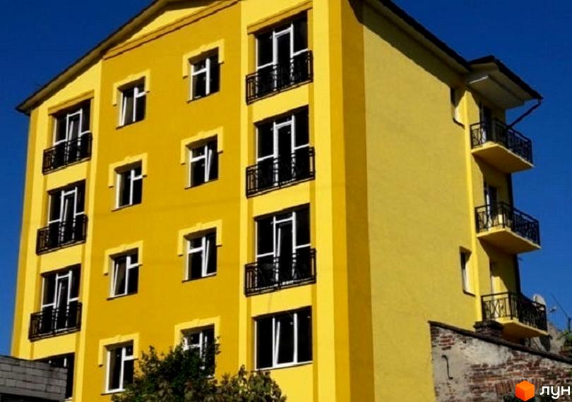 Яскрава жовта новобудова на вулиці Турянського, 27. Будинок має багато вікон та балконів з чорними огорожами. Навколо будинку видно зелені дерева та блакитне небо.