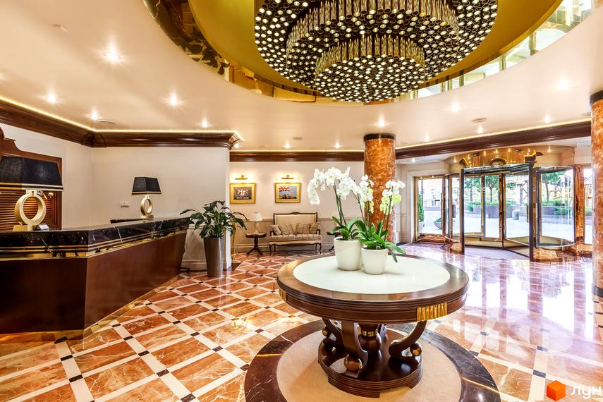 Просторий вестибюль Житлового комплексу Obolon Residences з мармуровою підлогою, великою люстрою, стійкою реєстрації та вхідними дверима.