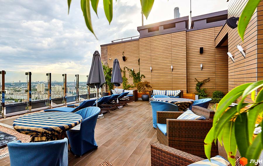 Тераса на даху Житлового комплексу Obolon Residences з дерев'яним фасадом, меблями для відпочинку та панорамним видом на місто.