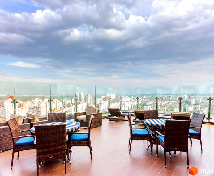 Тераса на даху Житлового комплексу Obolon Residences з плетеними меблями та оглядом на міську забудову.