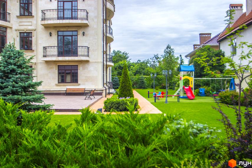 Клубний будинок Ліон з балконами та вікнами, поруч дитячий майданчик та зелена зона. Фото новобудови.