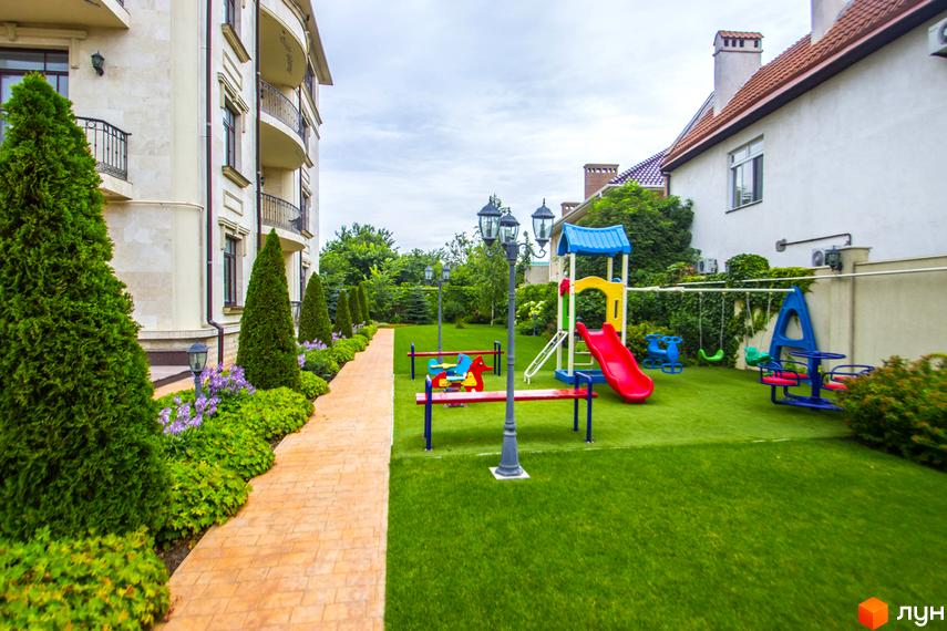 Клубний будинок „Ліон“ з елегантною фасадною обробкою та балконами. На прибудинковій території облаштовано сучасний дитячий майданчик із гіркою та гойдалками.