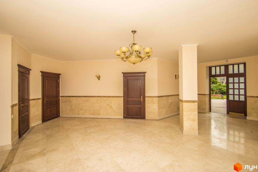 Клубний будинок „Ліон“: просторий хол з мармуровою підлогою, дерев'яними дверима та класичним освітленням. Вихід на прибудинкову територію з лавкою та зеленню.