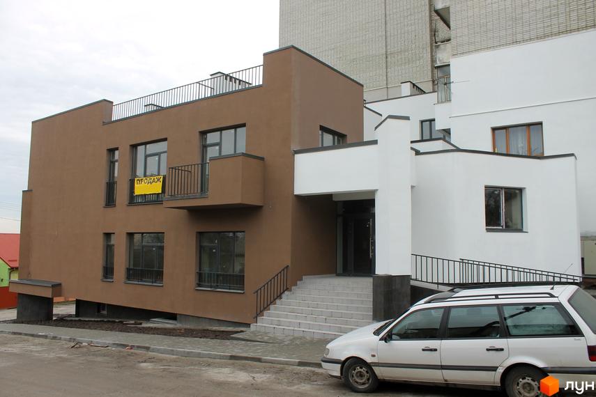 Фасад новобудови на вулиці Китайська, 14, з коричневими та білими елементами, балконами та великими вікнами. Поруч припаркований білий універсал.