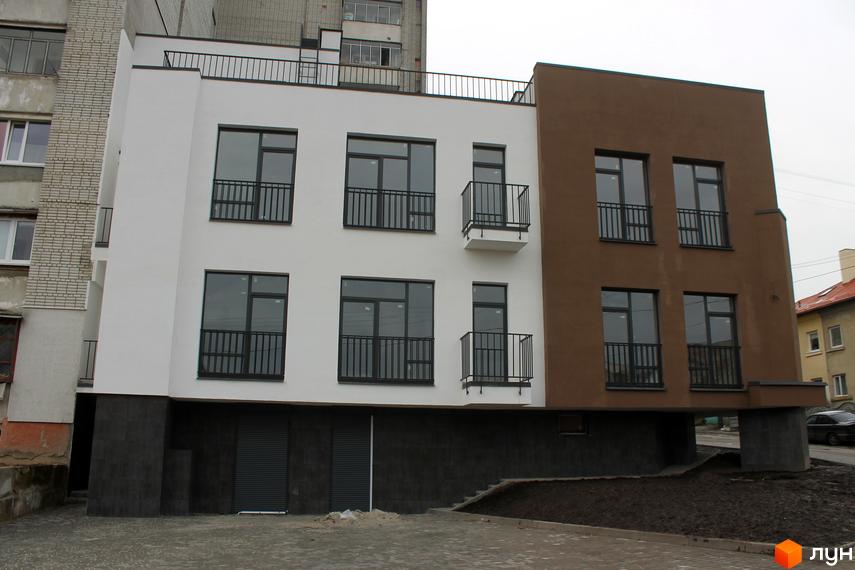 Новобудова на вулиці Китайська, 14. Будинок має білий та коричневий фасади, великі вікна з чорними рамами та балконами. Територія навколо будинку облаштована бруківкою та зеленими насадженнями.