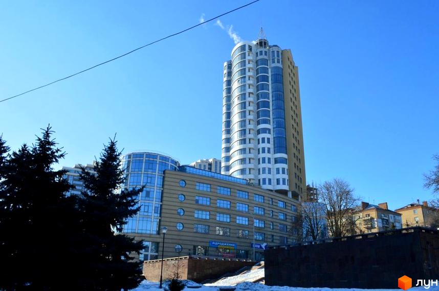 Житловий комплекс Магнат КМ з сучасним фасадом та прибудинковою територією, оточений зеленими насадженнями.