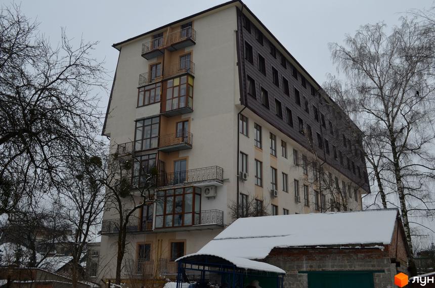 Житловий комплекс на вул. Гіпсова, 36в з бежевим фасадом, балконами та темним дахом. Зимовий пейзаж з деревами та снігом.