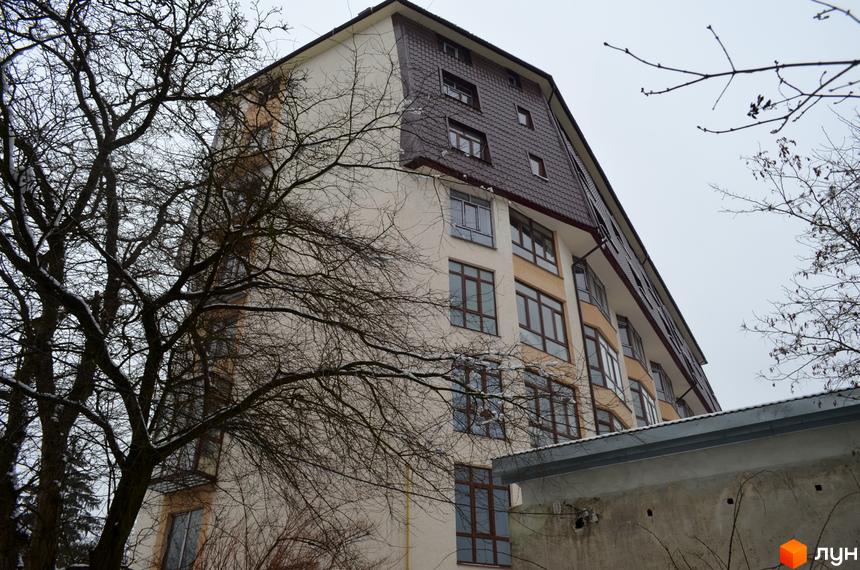 Багатоповерховий житловий комплекс на вул. Гіпсова, 36в з бежевим фасадом, похилим коричневим дахом та зимовими деревами.