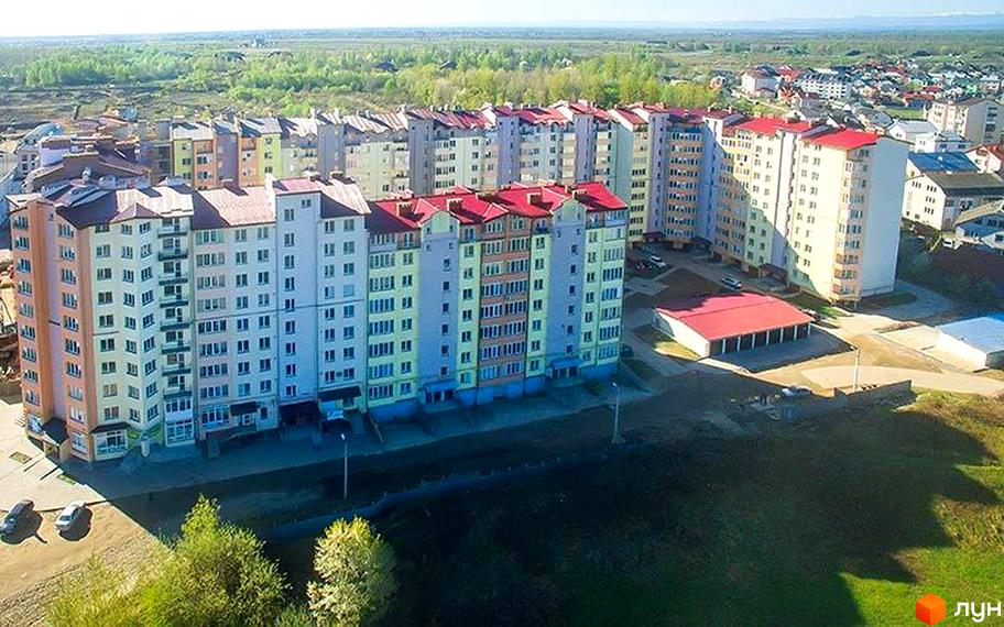 Житловий комплекс Квартал Виноградний з червоними дахами та різнокольоровими фасадами. Навколо будинку зелена територія.