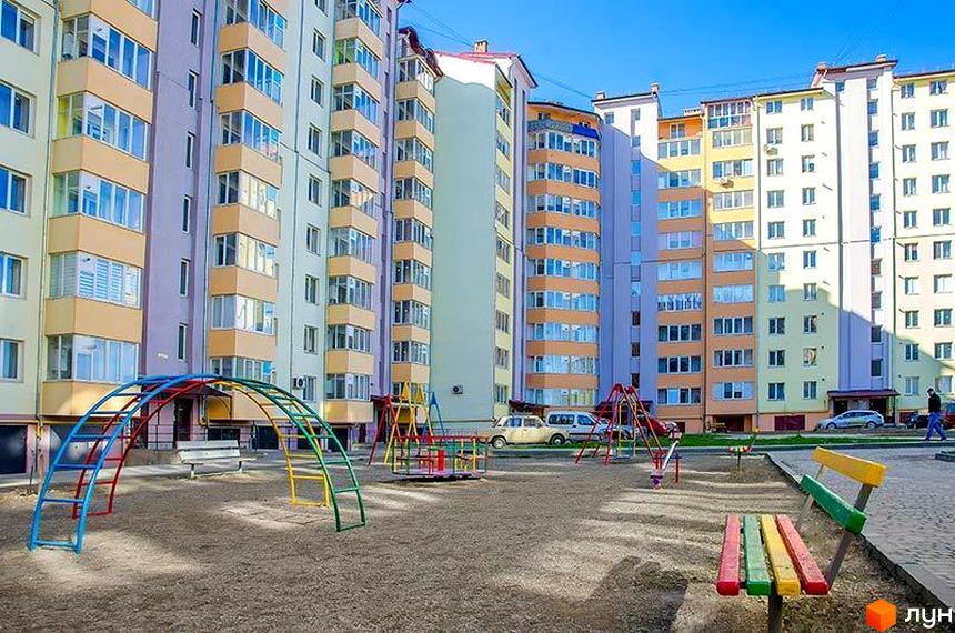 Зовнішній вигляд багатоповерхового будинку в Житловому комплексі Квартал Виноградний. На території дитячий майданчик з гірками та гойдалками.