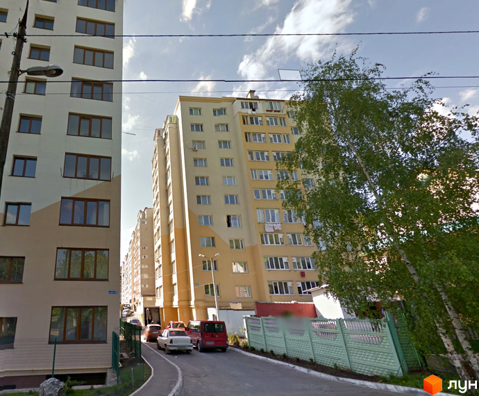 Зовнішній вигляд багатоповерхових житлових будинків на вулиці Перемоги, 8/4. Прибудинкова територія з дорогою та зеленими насадженнями.
