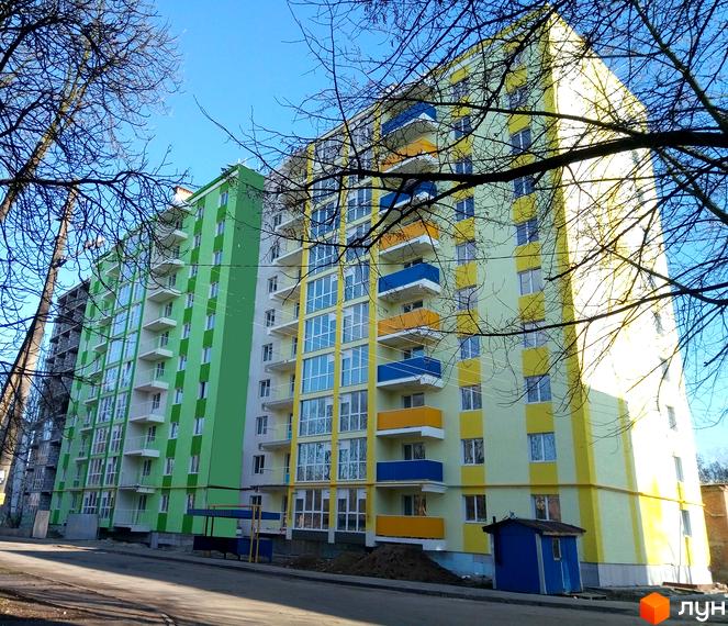 Фото фасаду будинку на вул. Текстильників, 26, 26/2. Багатоповерхова новобудова з кольоровими балконами та великими вікнами.