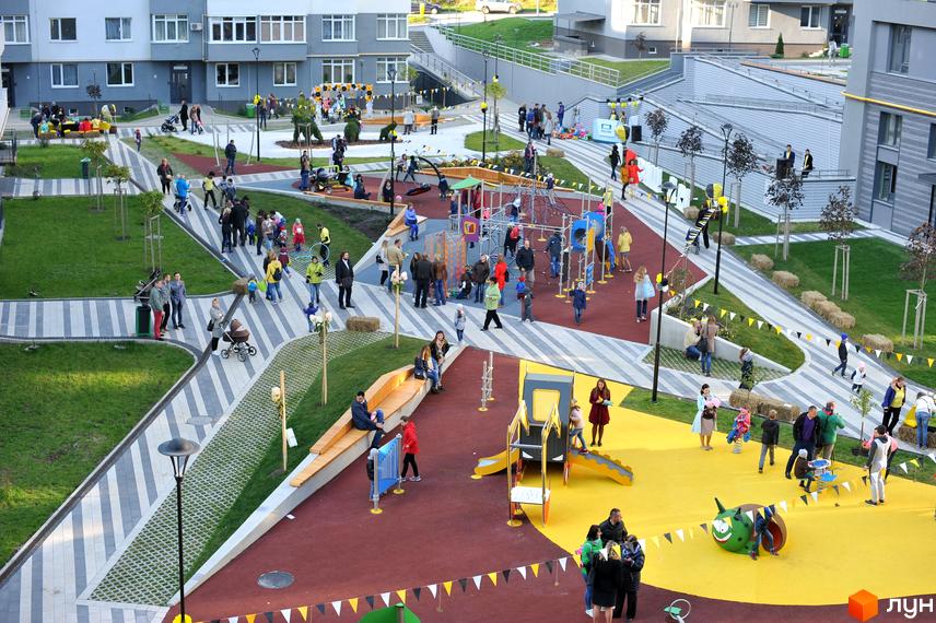 Житловий комплекс Пасічний: новий проєкт із сучасною архітектурою та облаштованою прибудинковою територією для відпочинку та ігор. На зображенні видно дитячий майданчик, зелені зони та місця для відпочинку.