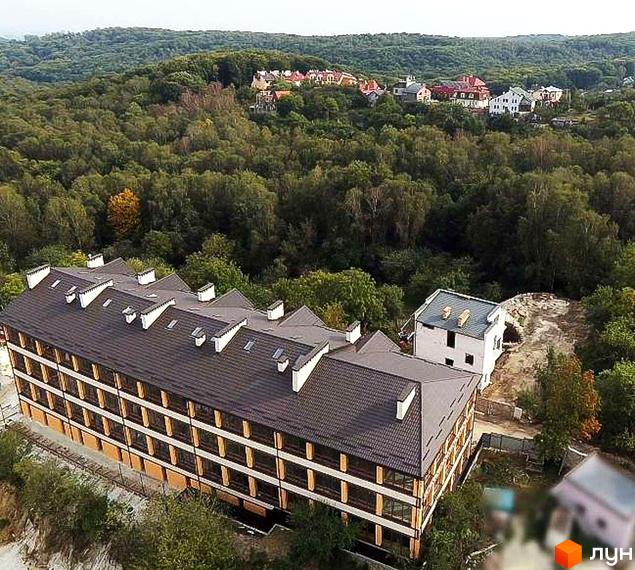 Фотографія житлового будинку на вулиці Лисенецька, 56. Багатоповерхова будівля з темним дахом та світлим фасадом, навколо дерева.