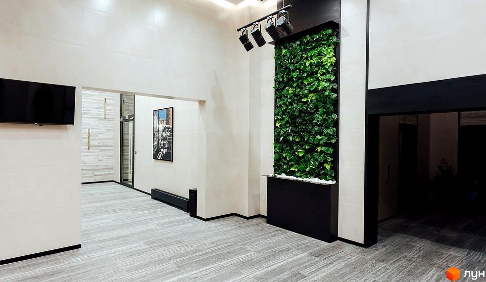 Інтер'єр холу Житлового комплексу New York Concept House з вертикальним озелененням та сірою плиткою на підлозі.