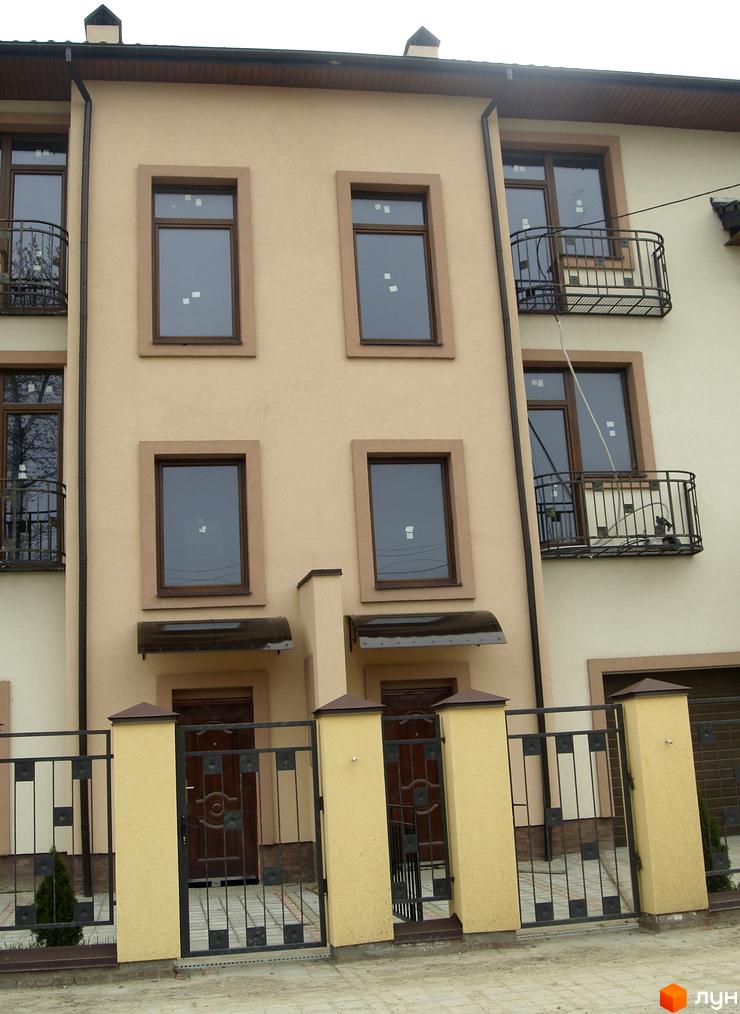 Зовнішній вигляд фасаду новобудови на вул. Янева, 5 з вікнами та балконами. Прибудинкова територія з огорожею та воротами.