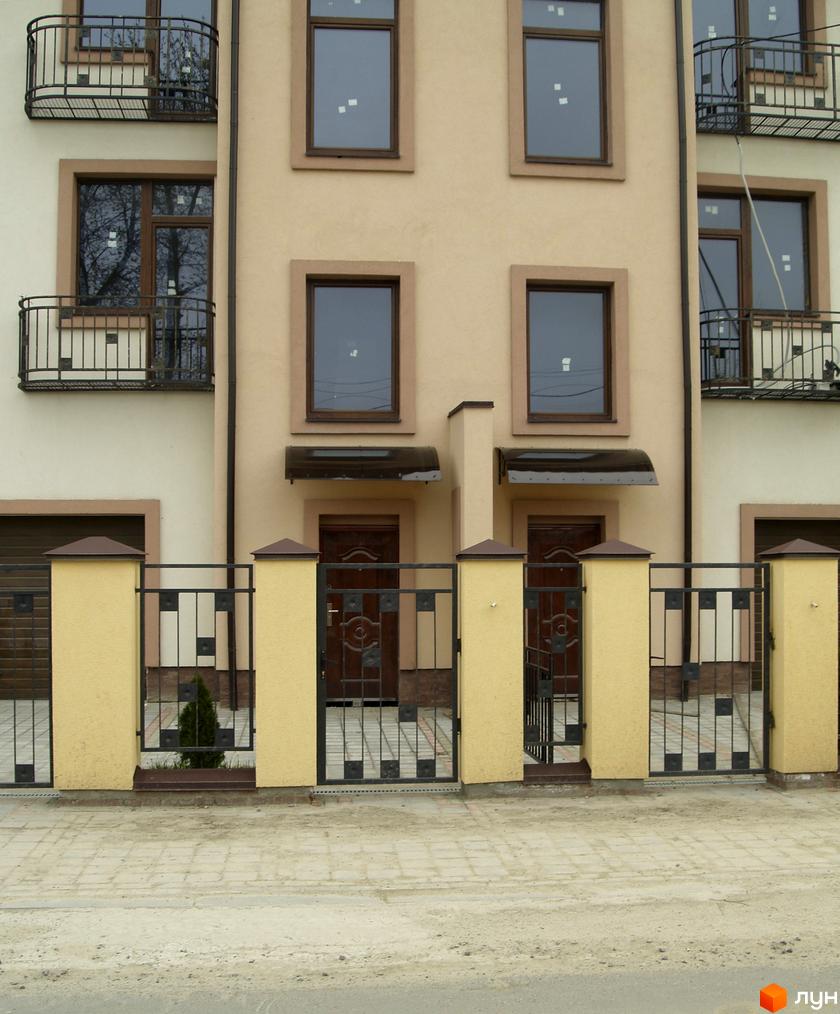 Фасад житлового комплексу на вул. Янева, 5. Огорожена територія з воротами та парканом.