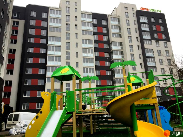 Житловий комплекс Контраст з яскравим фасадом та дитячим майданчиком. Новобудова має багато вікон та балконів, а також зелену зону для відпочинку.