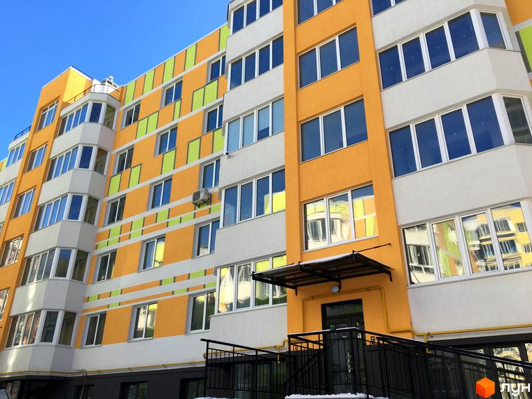 Зовнішній вигляд житлового комплексу Позитив з яскравим фасадом та великою кількістю вікон. Будинок має багатоповерхову структуру з балконами та лоджіями.