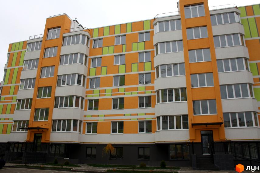 Житловий комплекс Позитив - яскрава фасадна система з помаранчевими та зеленими елементами. Багатоповерховий будинок з великою кількістю вікон та балконів.