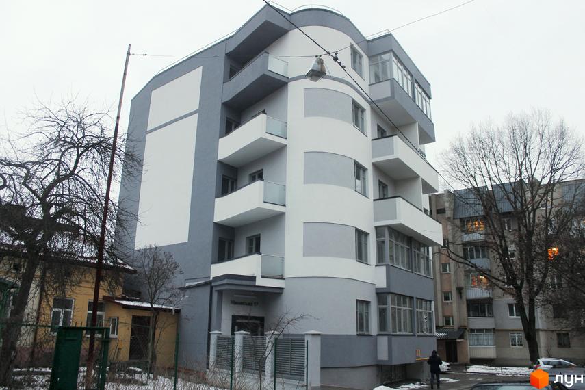 Фасад Клубного будинку Modern Lux з балконами та вигнутими лініями. Навколо видно дерева без листя та сніг на прибудинковій території.