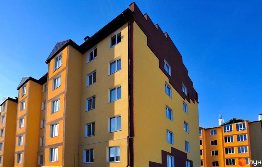 Житловий комплекс Спутник з яскравим фасадом на тлі блакитного неба. Багатоповерховий будинок з великими вікнами, що створюють відчуття простору.