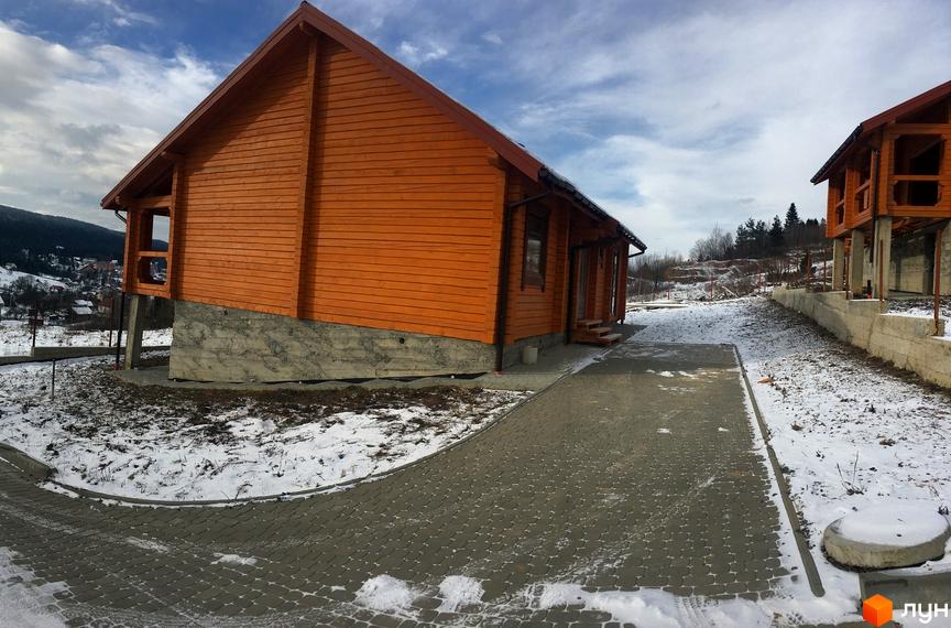 Дерев'яні будинки житлового комплексу на вулиці Грушевського, розташовані на схилі пагорба із засніженою прибудинковою територією та вимощеними доріжками.