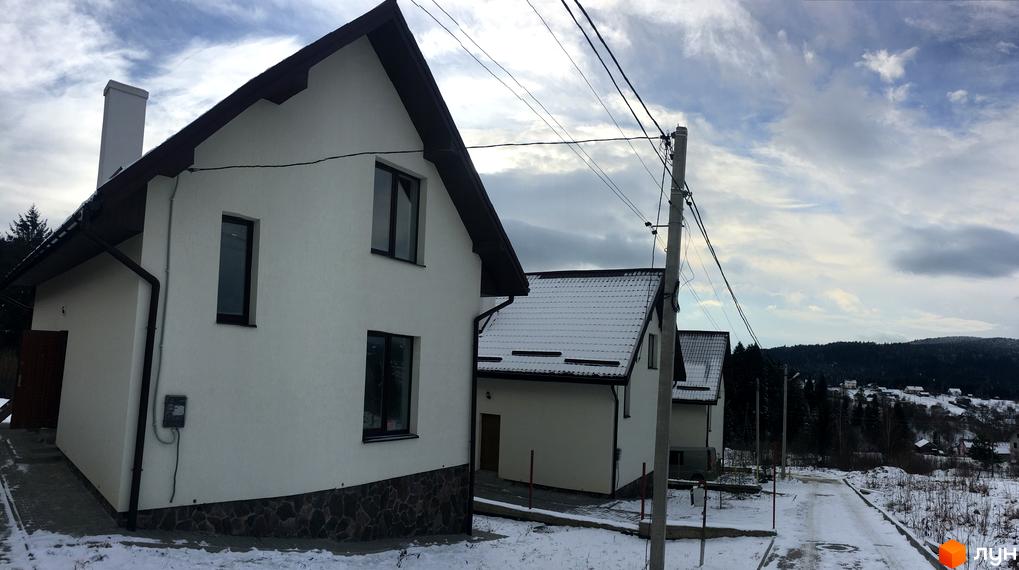 Зовнішній вигляд білих будинків житлового комплексу на вулиці Грушевського, з дахами, вкритими снігом. Навколо будинків розташована прибудинкова територія з дорогою та деревами.