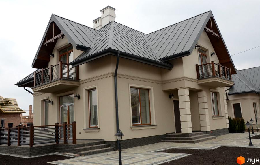 Зображення будинку в Котеджному містечку Провесінь. Двоповерховий будинок з балконом та сірим дахом, прибудинкова територія з тротуарною плиткою.