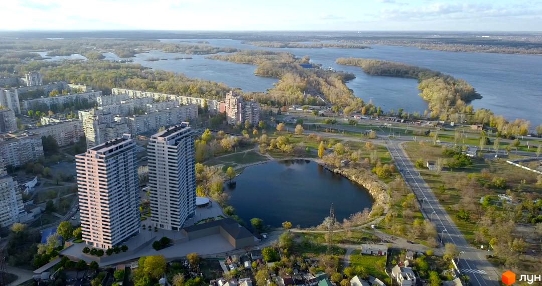 Панорамне фото Житлового комплексу Новокодацькi Вежi з висоти пташиного польоту. Видно висотні будинки, озеро, зелені насадження та дорогу.