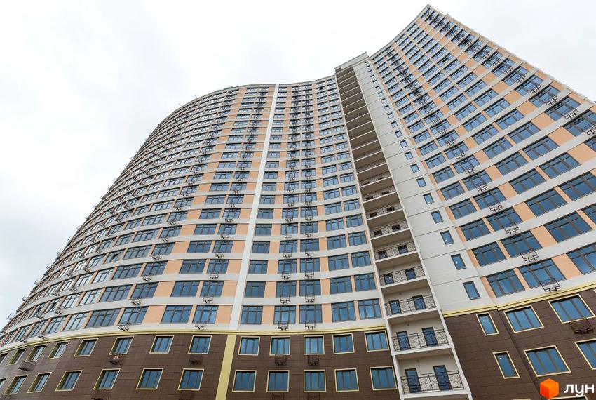 Зображення фасаду багатоповерхового будинку в Житловому комплексі Двадцять сьома перлина. Вигляд будівлі з великою кількістю вікон.