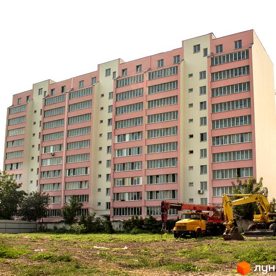Зовнішній вигляд багатоповерхового будинку ЖК Лелека-2 з рожевим фасадом та численними вікнами. На прибудинковій території видно будівельну техніку та зелені насадження.