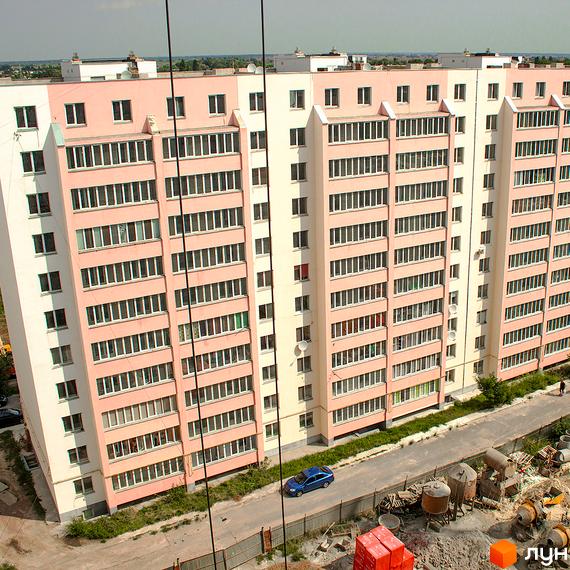 Житловий комплекс Лелека-2: рожева багатоповерхівка з білими вікнами та балконами, поруч дорога та зелена зона.