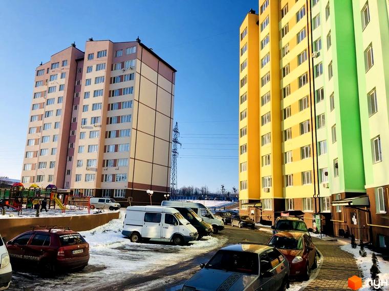 Житловий комплекс 4 Карата. Багатоповерхові будинки з яскравим фасадом, дитячий майданчик та парковка автомобілів.